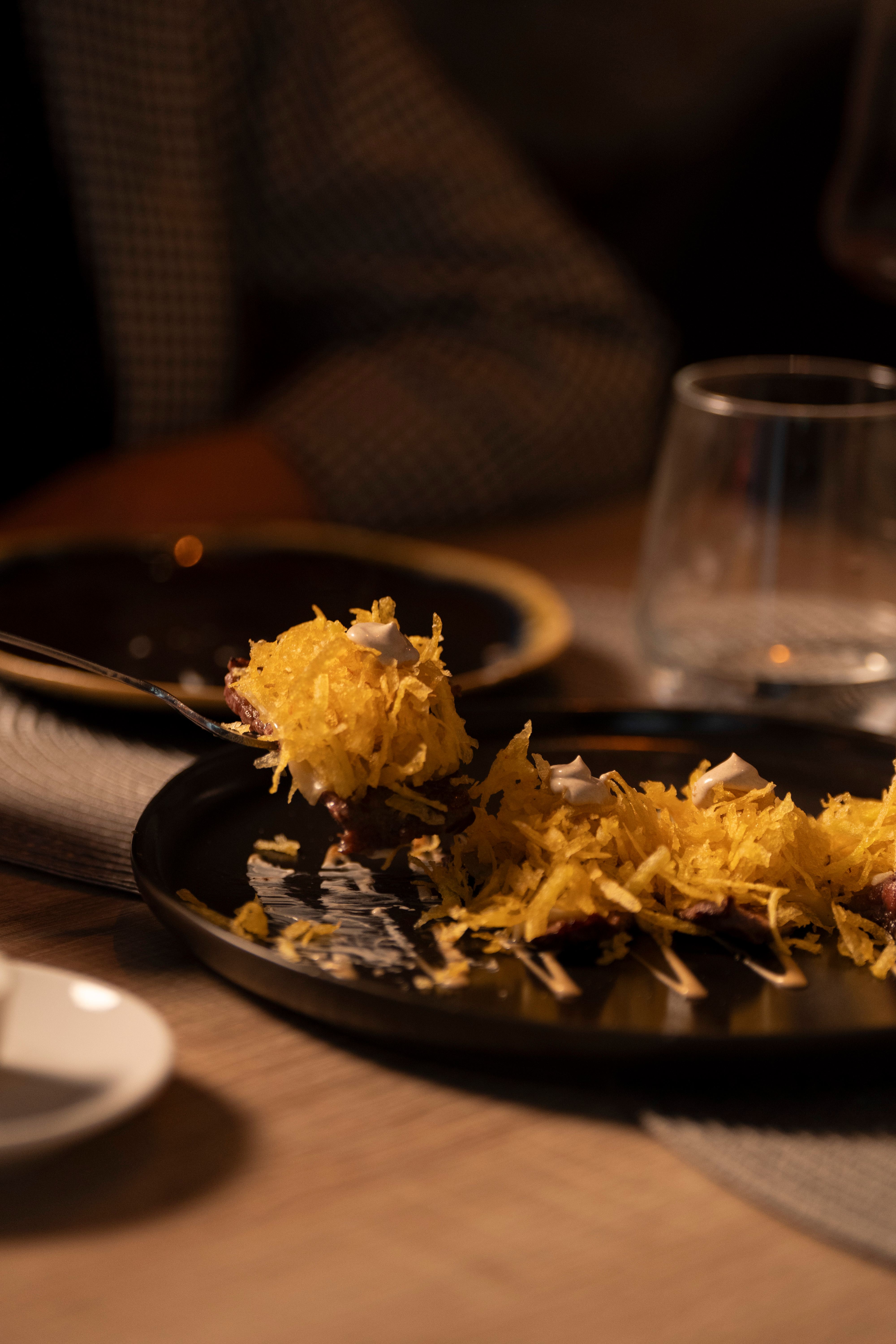 Huevos rotos con patata paja crujiente servidos en Vino y Verás